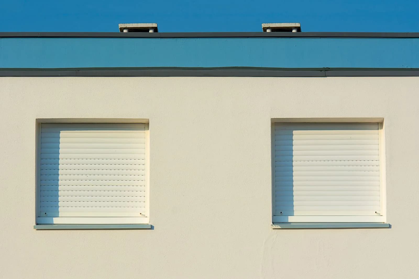 Zwei Fenster mit heruntergelassenen Außenrollläden